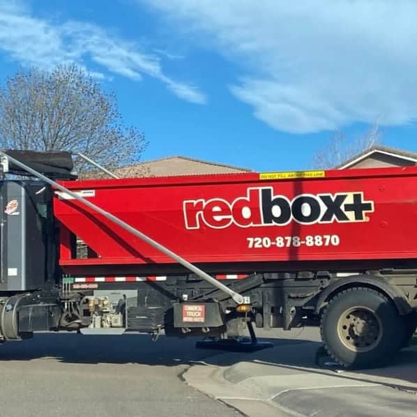 redbox+ Dumpsters of Denver South Metro truck providing roll-off dumpster hauling service in a residential neighborhood.