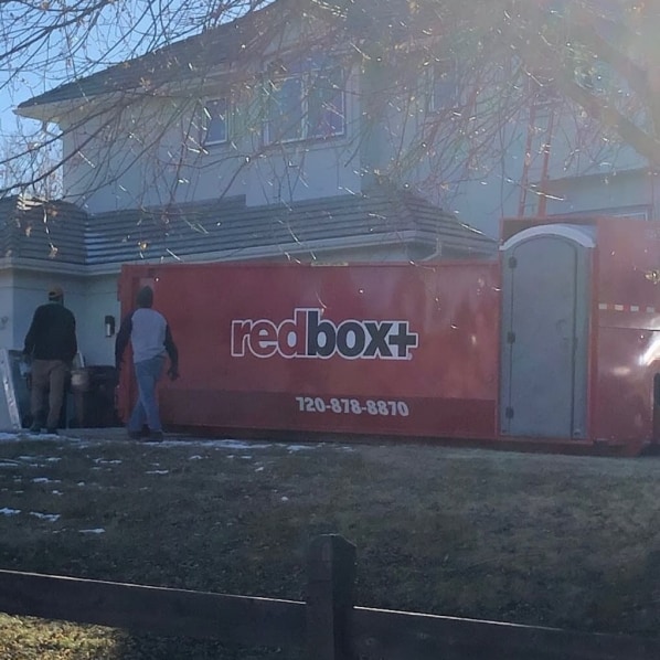 redbox+ Dumpsters of Denver South Metro delivering a roll-off dumpster to a residential property for a home renovation project.