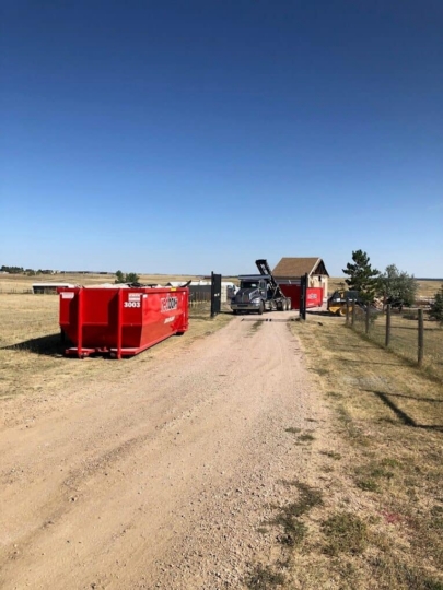 redbox+ Dumpsters of Denver South Metro truck delivering roll-off dumpsters to a rural home construction site in Elizabeth, CO.