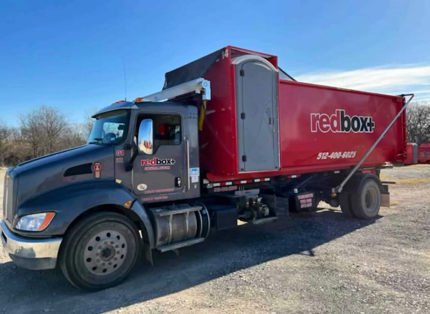 redbox+ roll-off truck hauling a dumpster