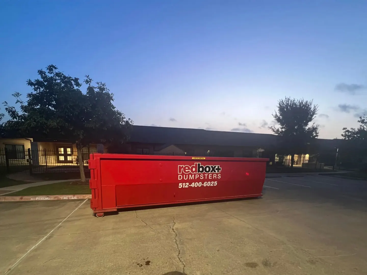 redbox+ roll-off dumpster on a job site at dusk