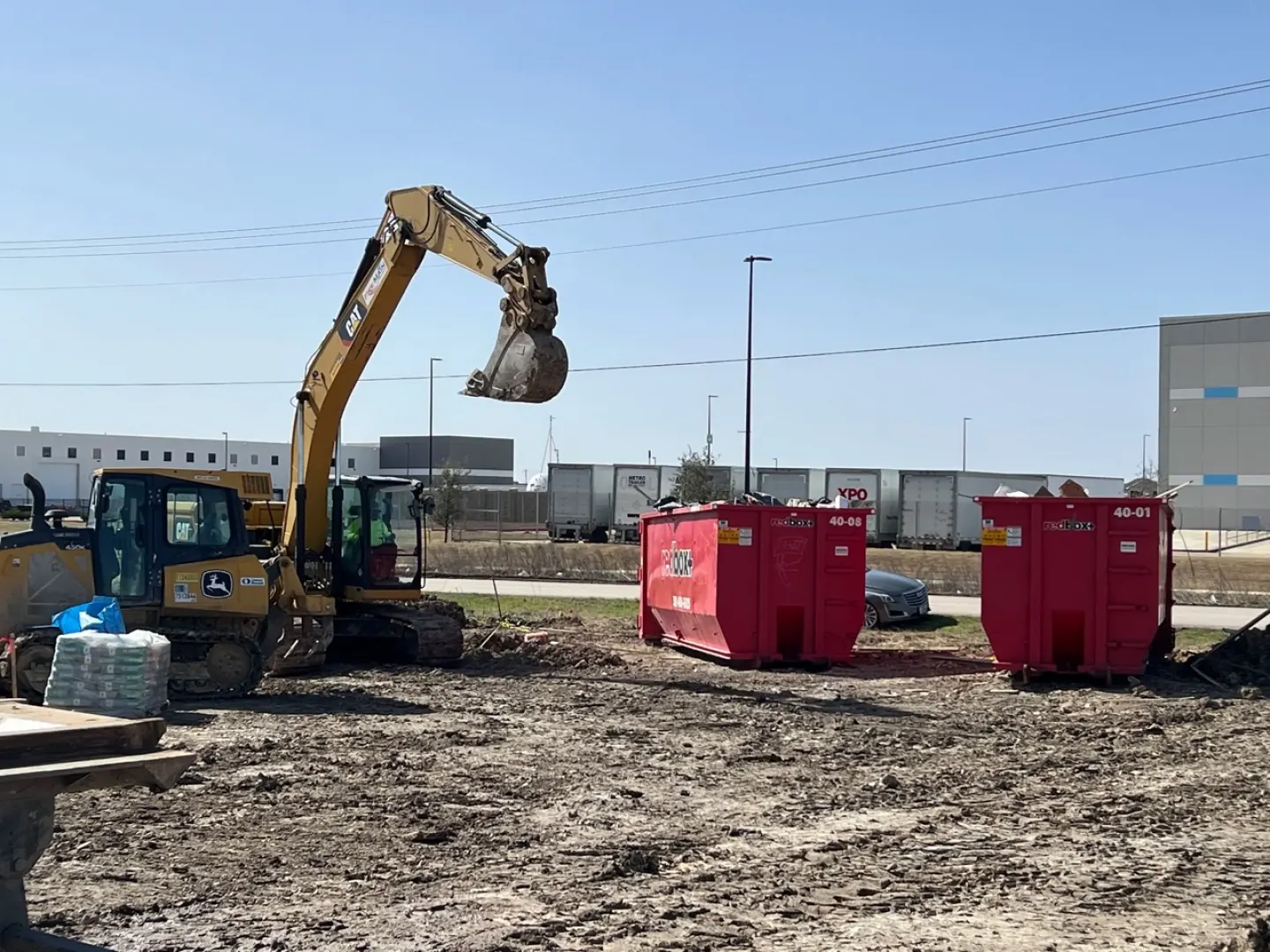 Excavator working next to redbox+ dumpsters