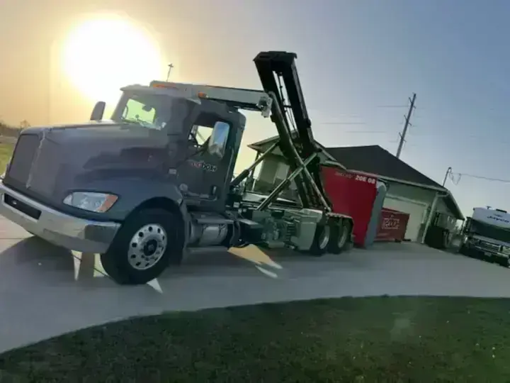 redbox+ roll-off truck delivering a dumpster to a home