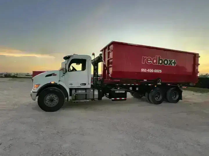 redbox+ roll-off truck carrying a dumpster