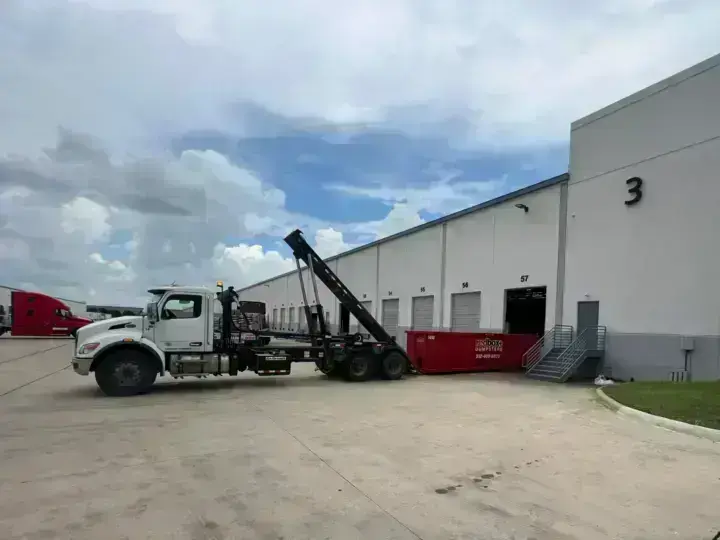 redbox+ roll-off truck at a warehouse loading dock