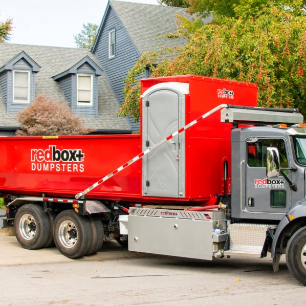redbox+ dumpster rental truck parked outside residential property