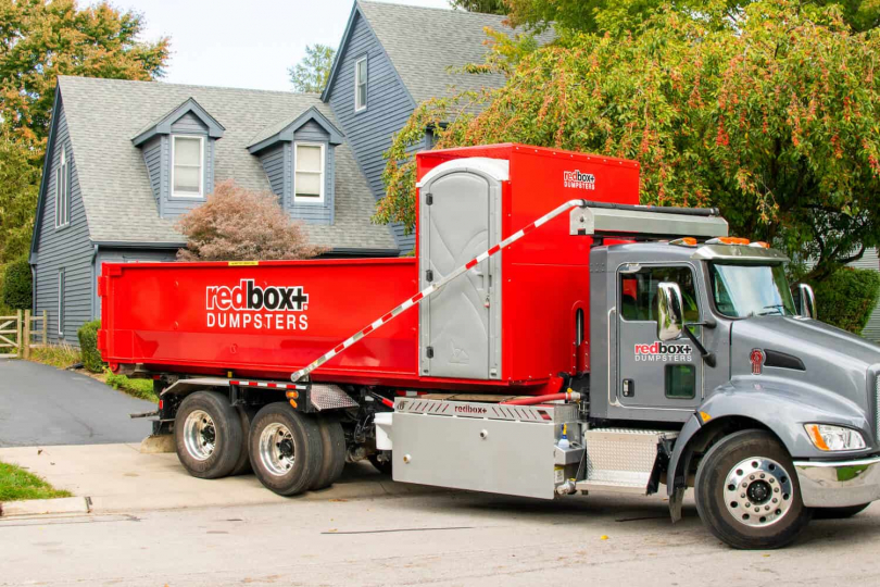 redbox+ dumpster rental truck parked outside residential property