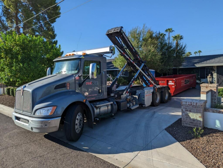 dumpster truck offloading dumpster in driveway phoenix