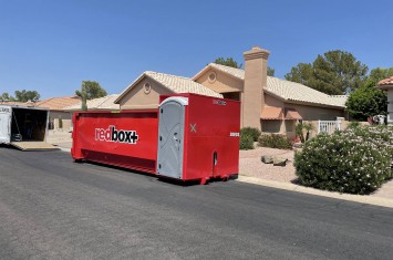 red elite dumpster rental with portable toilets in front of a house
