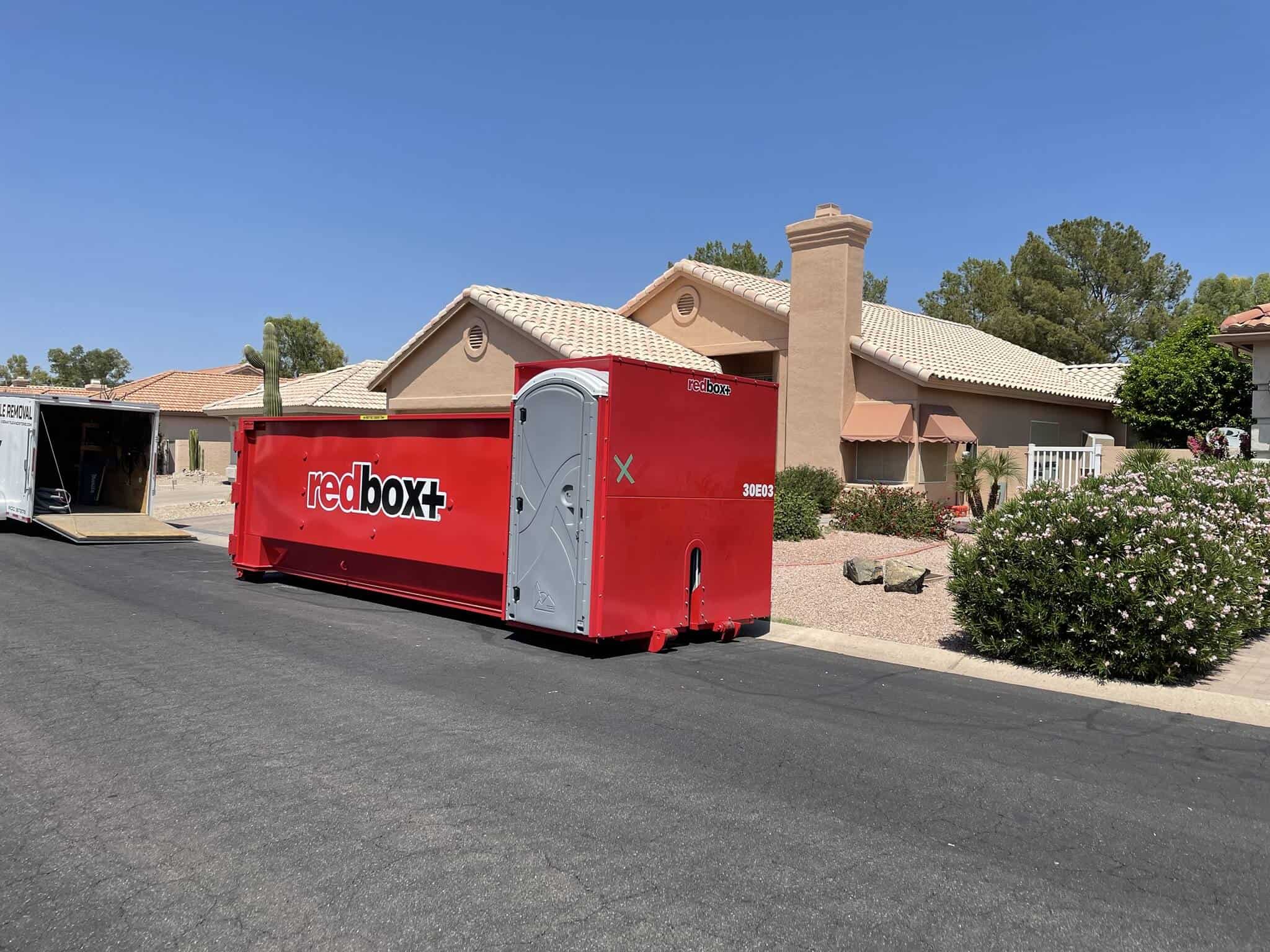 red elite dumpster rental with portable toilets in front of a house