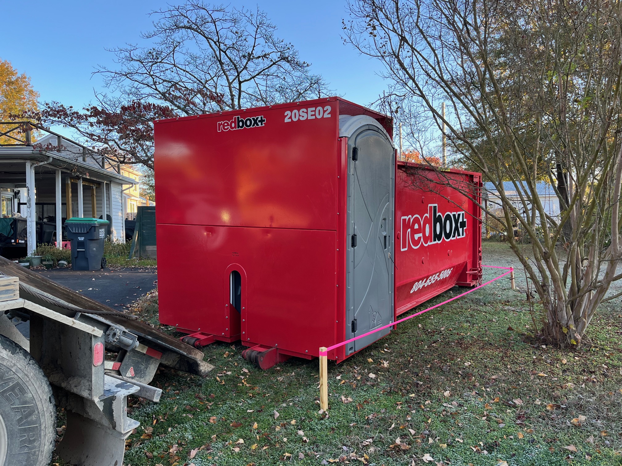 a redbox+ dumpster being delivered to a construction site