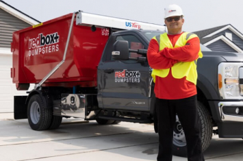 redbox+ employee standing in front of truck with redbox+ dumpster in tow